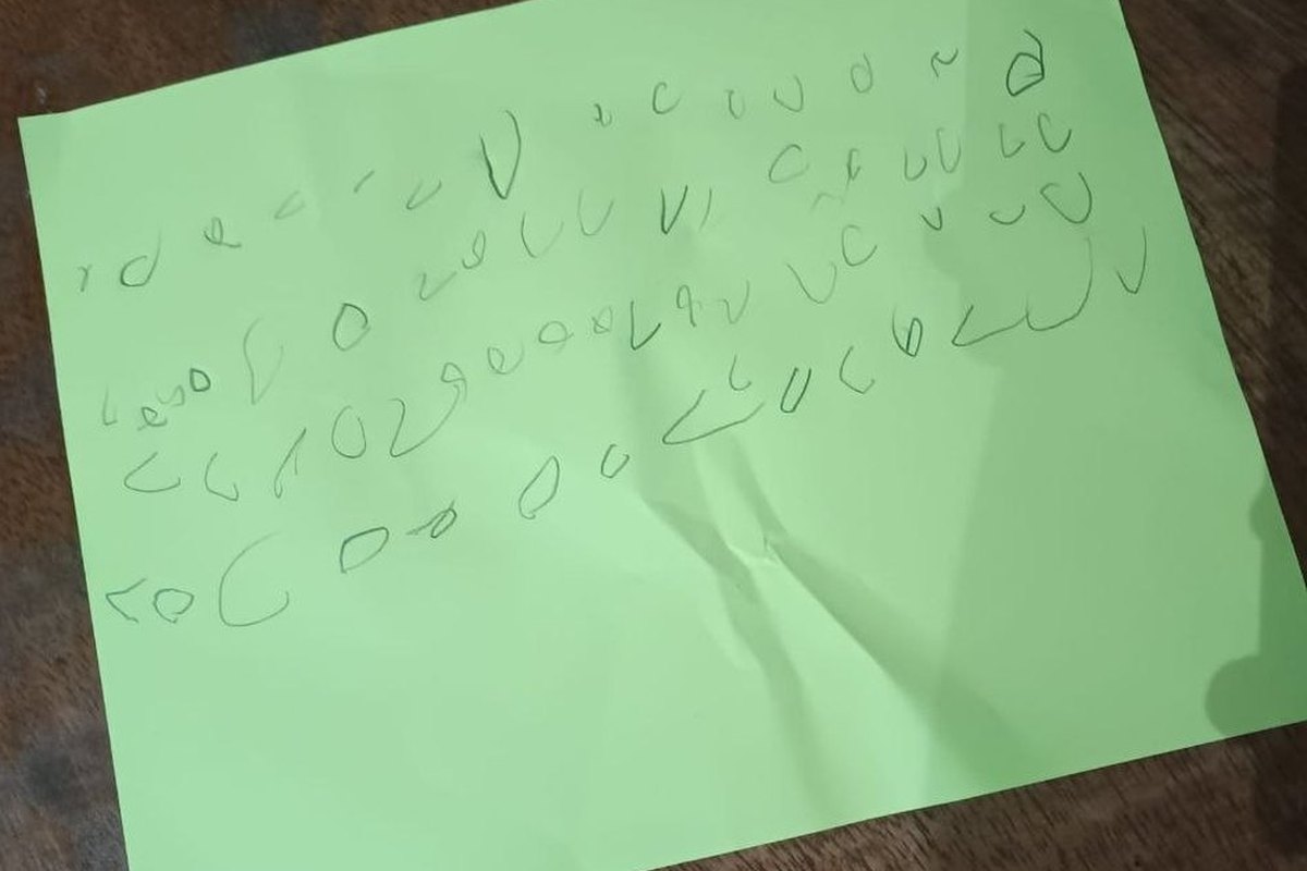 A sheet of green paper covered in rows of a child&rsquo;s invented symbols